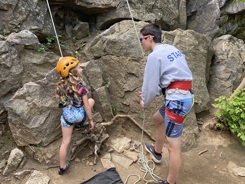 A child and camp counselor rock climb.