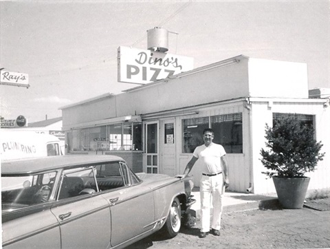 A person stands in front of Dino's Pizza.