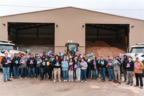 Group shot of Public Works employees and students standing outside holding thank you cards