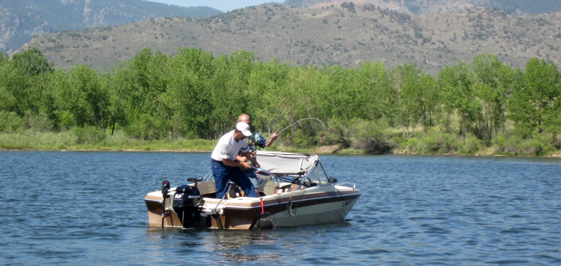 Two people catch a trout in a boat during the tournament.
